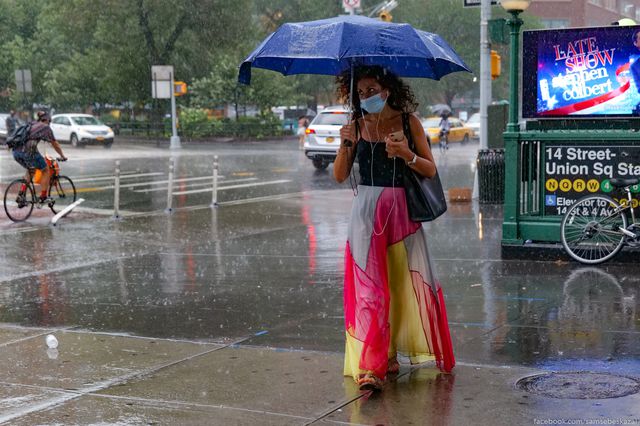 Woman wears mask around Union Square during recent downpour.
